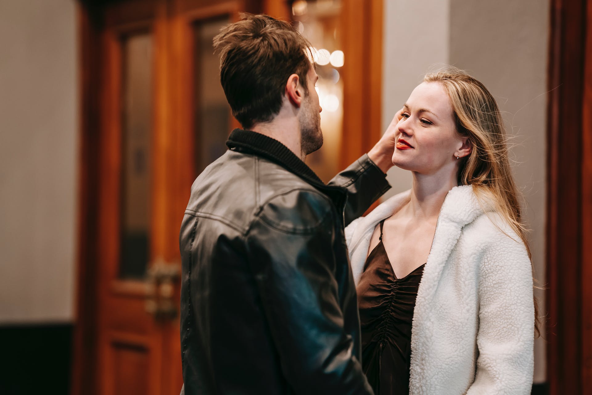 A woman smiling as a man tucks her hair behind her ear